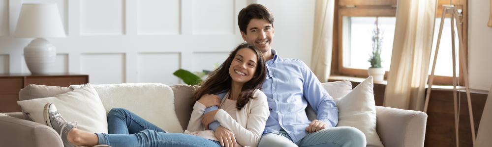 Screen renters to help ensure your investment will be respected. This is a photo of a happy couple lounging on a couch in their new apartment. 